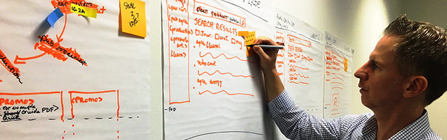 Stakeholder writing on a low-fidelity prototype of a potential digital product.